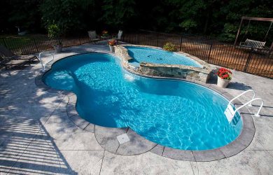 Curvilinear splash deck with deck bubblers and one spillover cascade for a fiberglass pool